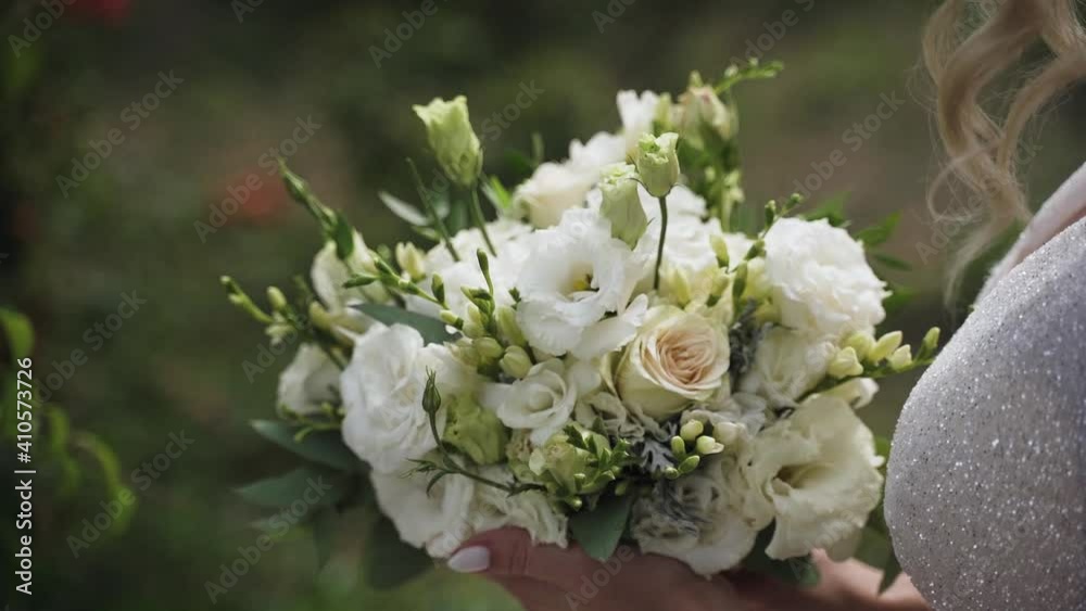 Bride in white dress holds wedding bouquet of white flowers Bride in white dress holds wedding bouquet of white flowers
