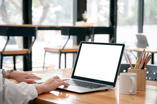 Cropped image of woman hands working on laptop computer while sitting at the table in co-workspace.