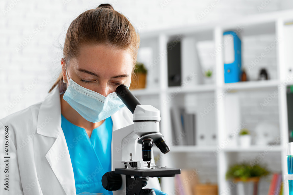 Young woman scientist using microscope in laboratory
