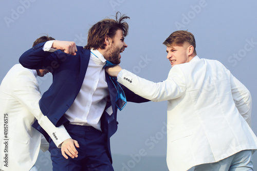 Crazy business man fighting. Young people fighting in nature on blue sky background.