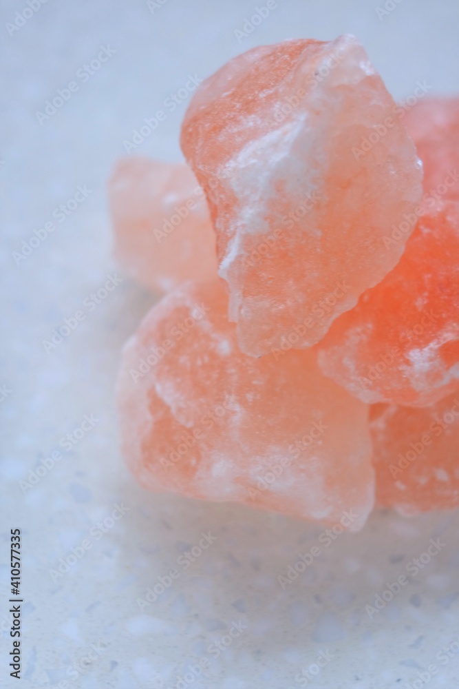 Fototapeta premium Pink himalayan salt pieces close-up on a marble background.Pink crystal salt