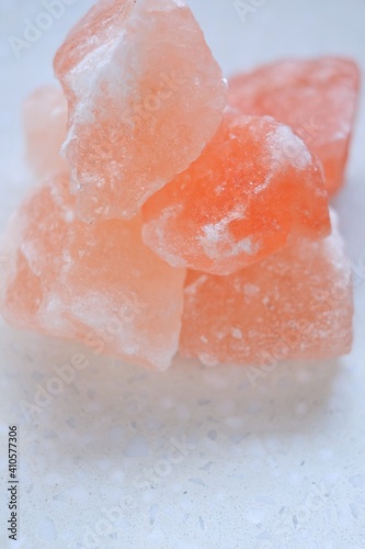 Pink himalayan salt pieces on a light marble background.Pink crystal salt