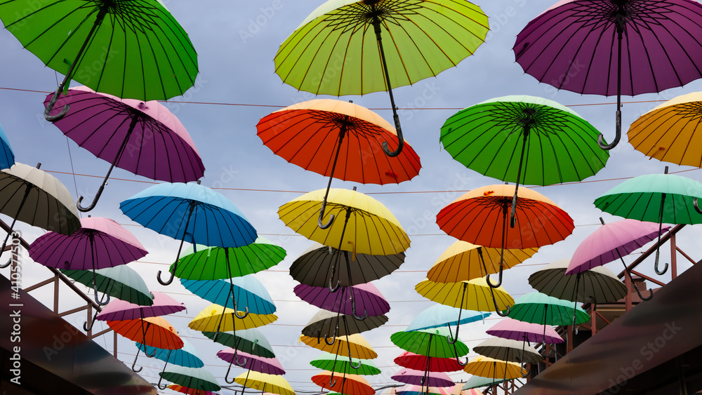 many colorful umbrellas hanging in the sky above the alley