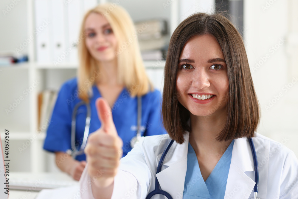 Beautiful smiling female doctor showing OK or approval sign with thumb up closeup. High level therapeutist consultation, best treatment, healthy lifestyle, satisfied patient, physical exam concept Beautiful smiling female doctor showing OK or approval sign with thumb up closeup. High level therapeutist consultation, best treatment, healthy lifestyle, satisfied patient, physical exam concept