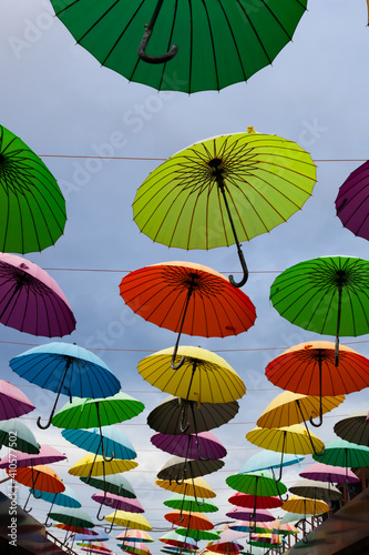 many colorful umbrellas hanging in the sky above the alley