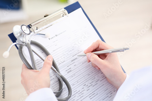 Female doctor hand hold silver pen filling patient list at clipboard pad closeup. Physical  exam  er  disease prevention  ward round  visit check  911  prescribe remedy  healthy lifestyle concept