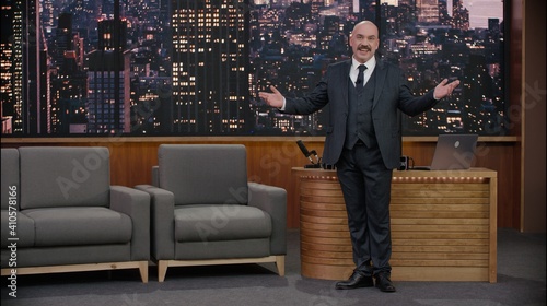 Late-night talk show host is performing his monologue, looking into camera. TV broadcast style show. Model and property released for commercial use.