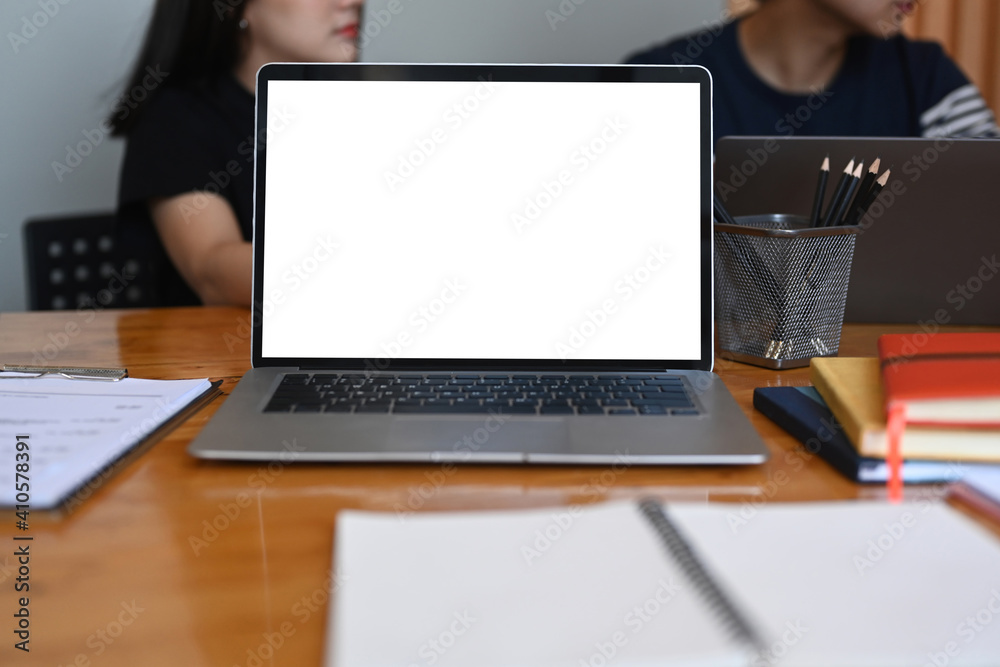Close up view of laptop computer with blank screen and business people sitting in background. Close up view of laptop computer with blank screen and business people sitting in background.