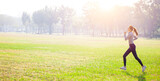 Young beautiful woman running on grass field at morning