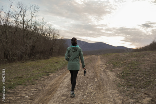 Girl tourist hiker walks along the village road