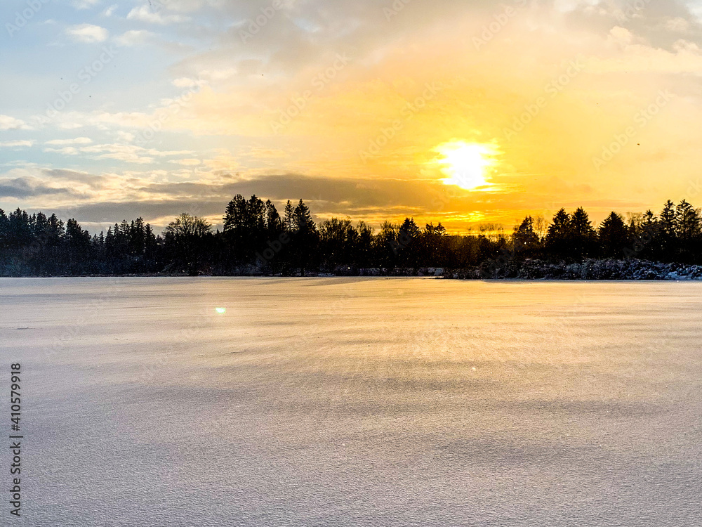 Abstrakter Sonnenuntergang über verschneitem Feld mit Schneeverwehungen