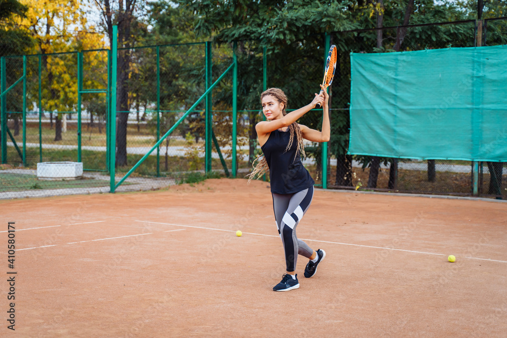 Professional tennis player doing sport on the court. She's about to hit the ball, suspended in the air, with racket. Tennis player in action. It takes a lot of energy and strength to win a match