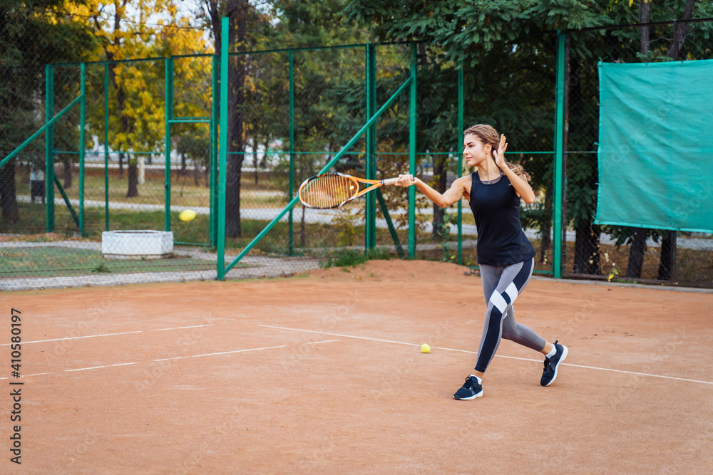 Professional tennis player doing sport on the court. She's about to hit the ball, suspended in the air, with racket. Tennis player in action. It takes a lot of energy and strength to win a match