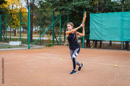 Professional tennis player doing sport on the court. She's about to hit the ball, suspended in the air, with racket. Tennis player in action. It takes a lot of energy and strength to win a match © Daria