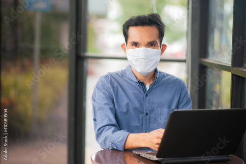 Asian businessman wear facemask working laptop computer in office