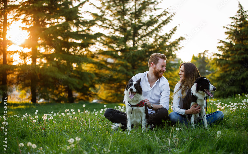 Happy young couple walking, playing with dogs in a park Happy young couple walking, playing with dogs in a park
