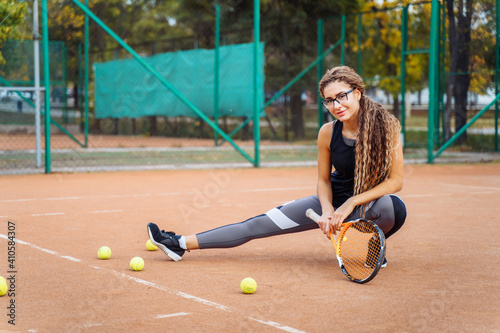 Warm up with tennis racket before starting your workout. The charming tennis player warms up the muscles before giving them physical activity. Tennis can be traumatic if the precautions are not taken © Daria