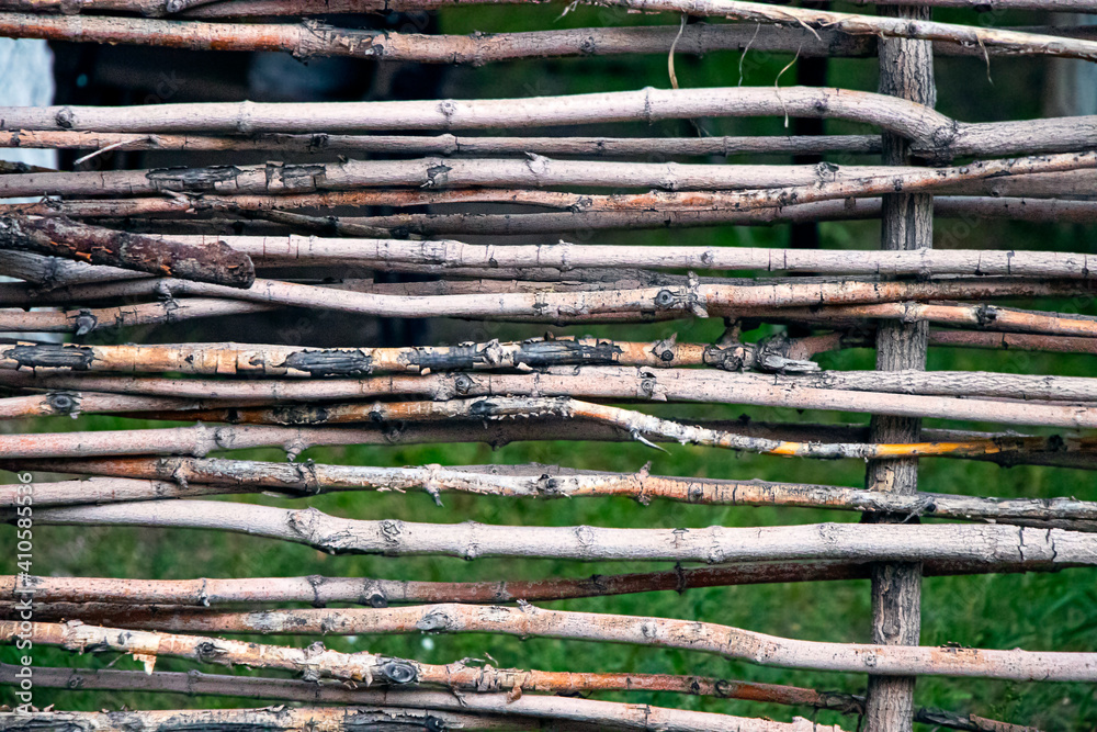 Close-up fence made of wooden rods. Wicker fence made of twigs. Natural rustic fence made of branches. Close-up fence made of wooden rods. Wicker fence made of twigs. Natural rustic fence made of branches.