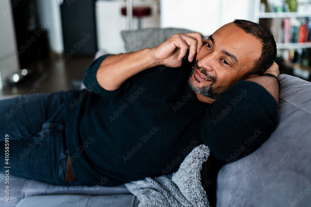 40 years old man relaxing on the sofa at home and talking on the phone 40 years old man relaxing on the sofa at home and talking on the phone