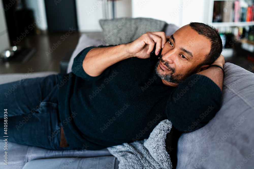 Obraz premium 40 years old man relaxing on the sofa at home and talking on the phone