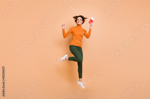 Full size photo of young beautiful excited smiling happy positive girl jump with passport in hand isolated on beige color background