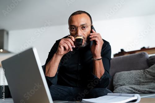 Serious man drinking coffee while managing accounts at home