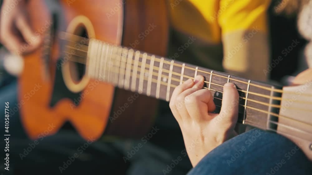 Slow-motion cinematic close-up shot of kid's hands playing chords on the guitar. Slow-motion cinematic close-up shot of kid's hands playing chords on the guitar.