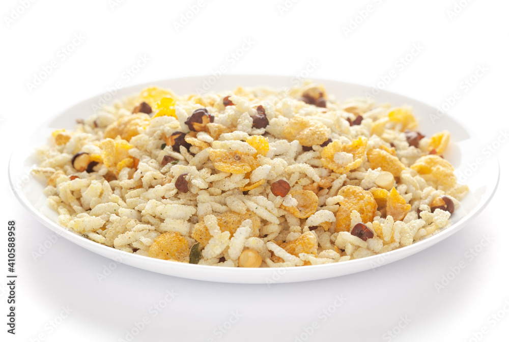Crunchy Diet Lite Mixture in a white ceramic plate made with Puffed Rice, Corn Flakes, and Curry leaves. Pile of Indian spicy snacks (Namkeen), under backlight, side view, Crunchy Diet Lite Mixture in a white ceramic plate made with Puffed Rice, Corn Flakes, and Curry leaves. Pile of Indian spicy snacks (Namkeen), under backlight, side view,