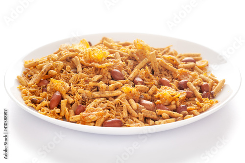 Spicy Chatpata Mixture in a white ceramic plate made with peanuts, corn flakes, etc. Pile of Indian spicy snacks (Namkeen), under backlight, side view, 