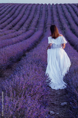 Among the lavender fields. A beautiful girl runs against the background of a large lavender field