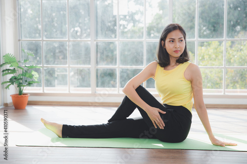 Asian young beautiful woman practicing Yoga and exercising on mat at home, Indoor sports activity