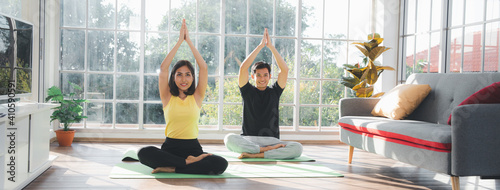 Couple of Asian boy and Asian young girl practicing yoga on mats in living room at home