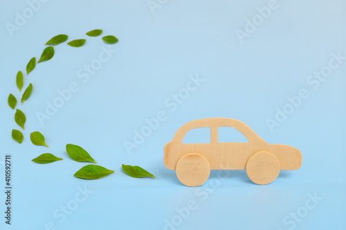 Obraz na plátně Wooden car model emitting fresh green leaves on blue background