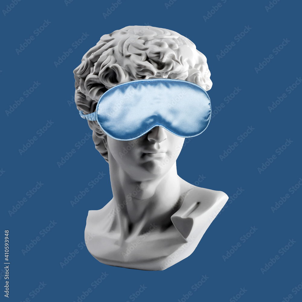 Gypsum statue of David head in blue sleep mask. Plaster copy of David's  head in sleeping