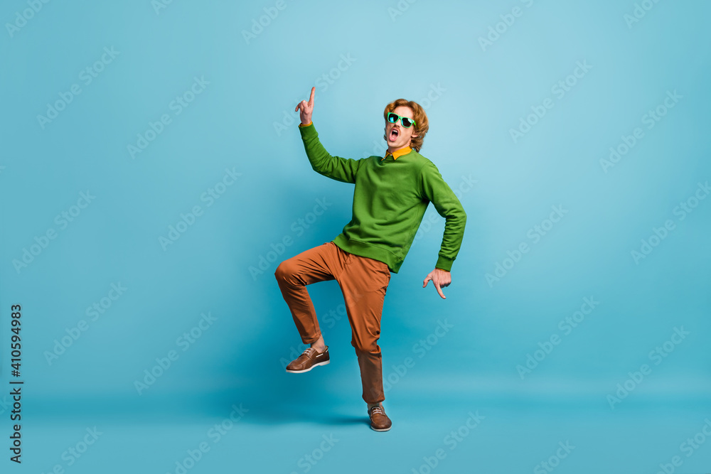 Full size photo of young funky funny excited careless carefree crazy man in sunglasses dancing isolated on blue color background