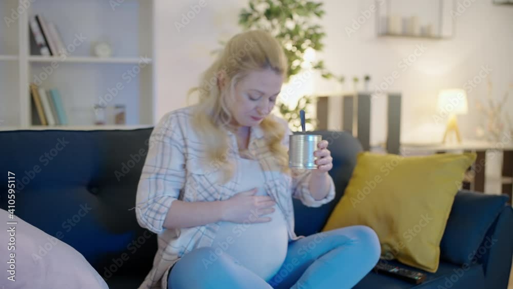 Expecting woman eating canned food at home, stroking pregnant belly, nutrition Expecting woman eating canned food at home, stroking pregnant belly, nutrition