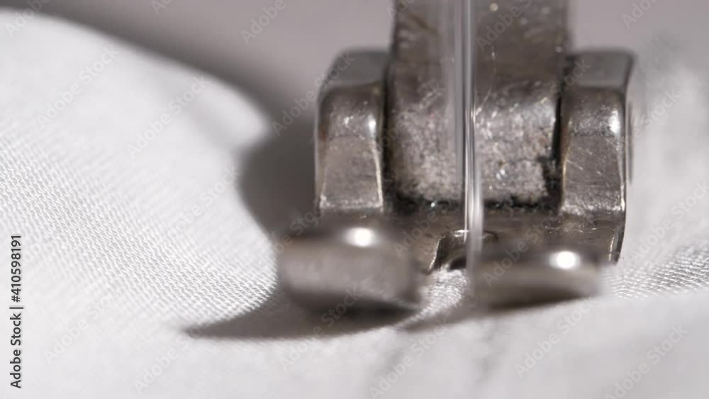 Macro slow motion detail shot of a sewing machine needle penetrating white fabric with fine white thread, Macro slow motion detail shot of a sewing machine needle penetrating white fabric with fine white thread,