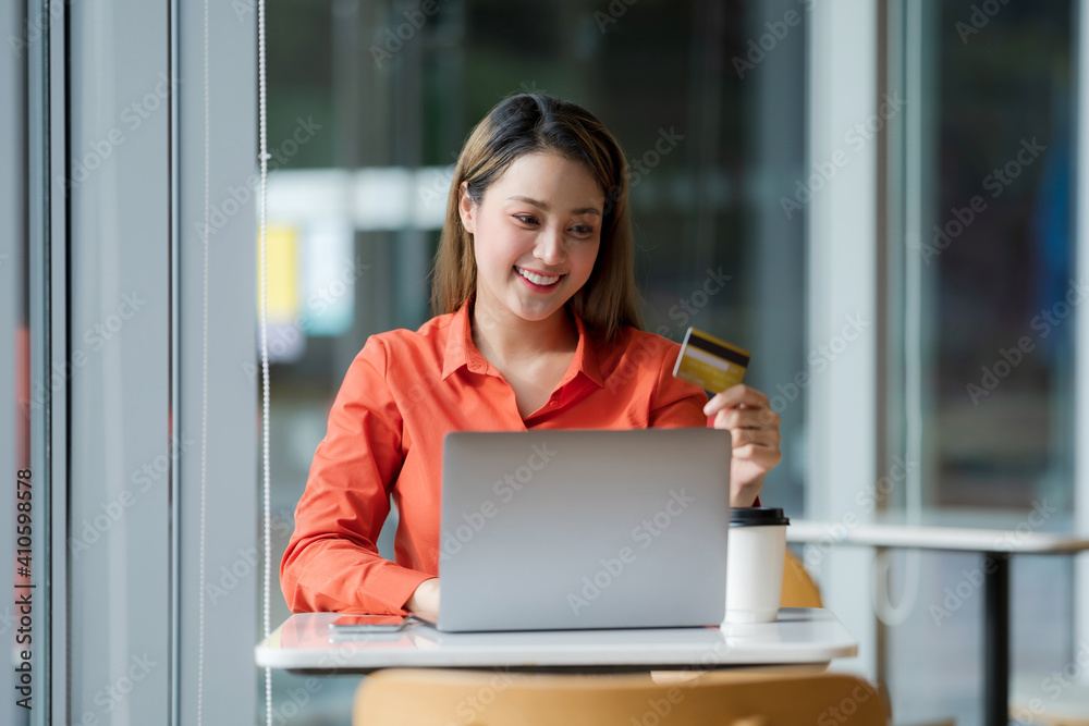 Portrait of Happy woman using laptop with credit card and smiling face in creative office Portrait of Happy woman using laptop with credit card and smiling face in creative office