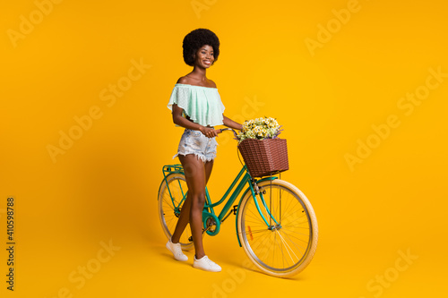 Photo portrait full body view of girl with bicycle isolated on vivid yellow colored background