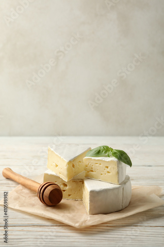 Baking paper with camembert cheese, basil and dipper on wooden background