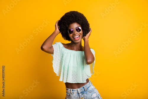 Photo portrait of woman touching hair isolated on vivid yellow colored background