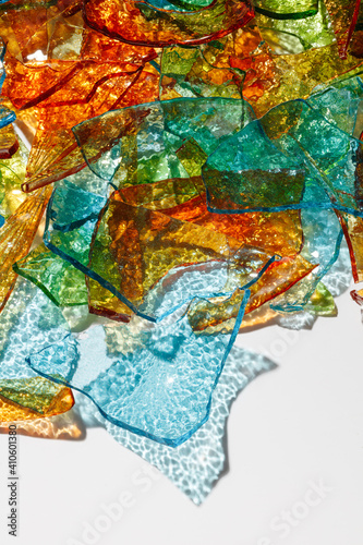 Mosaic of Broken Glass. Background of fragments of colored multicolored glass with blurred reflections on white background. Selective focus