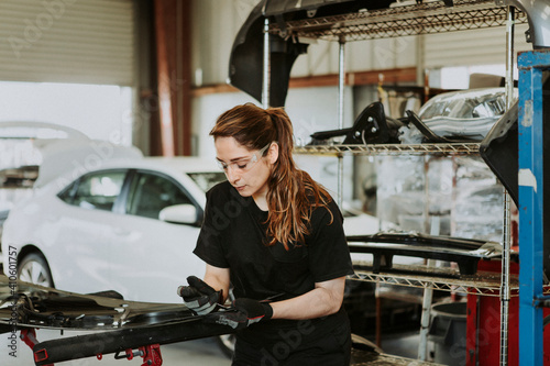 Female technician fixing car parts in a garage