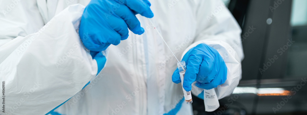 Focused nurse wearing protective suit and gloves holding equipment to practice a swab. Coronavirus, covid-19 test. Focused nurse wearing protective suit and gloves holding equipment to practice a swab. Coronavirus, covid-19 test.