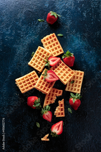 Waffles with fresh juicy strawberries on a dark blue background.