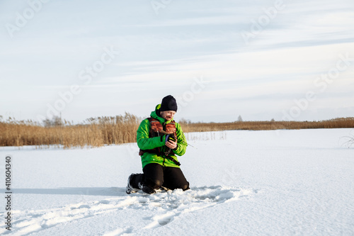 young man on a winter fishing trip on a snowy lake fishes on a fishing rod