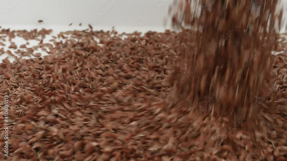 Close shot of dropping flax seeds over white background Close shot of dropping flax seeds over white background