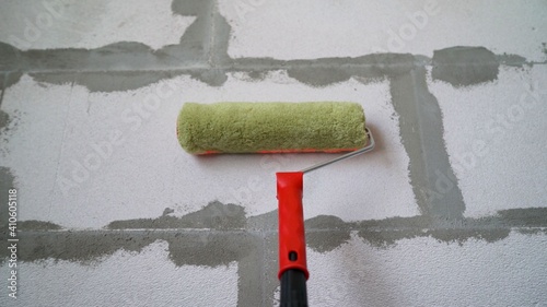 Roller and foam block. A construction roller with a fur nozzle on the background of a wall made of aerated blocks. The roller stands on a concrete wall made of foam blocks.