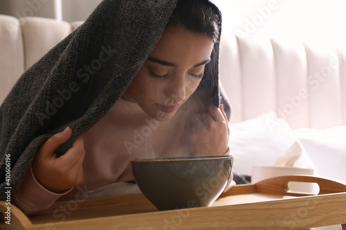 Woman with plaid doing inhalation above bowl indoors photo