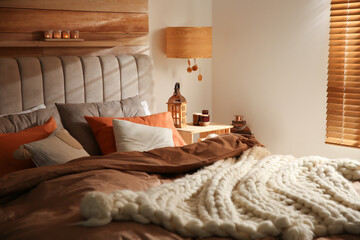 Cozy bedroom interior with knitted blanket and cushions